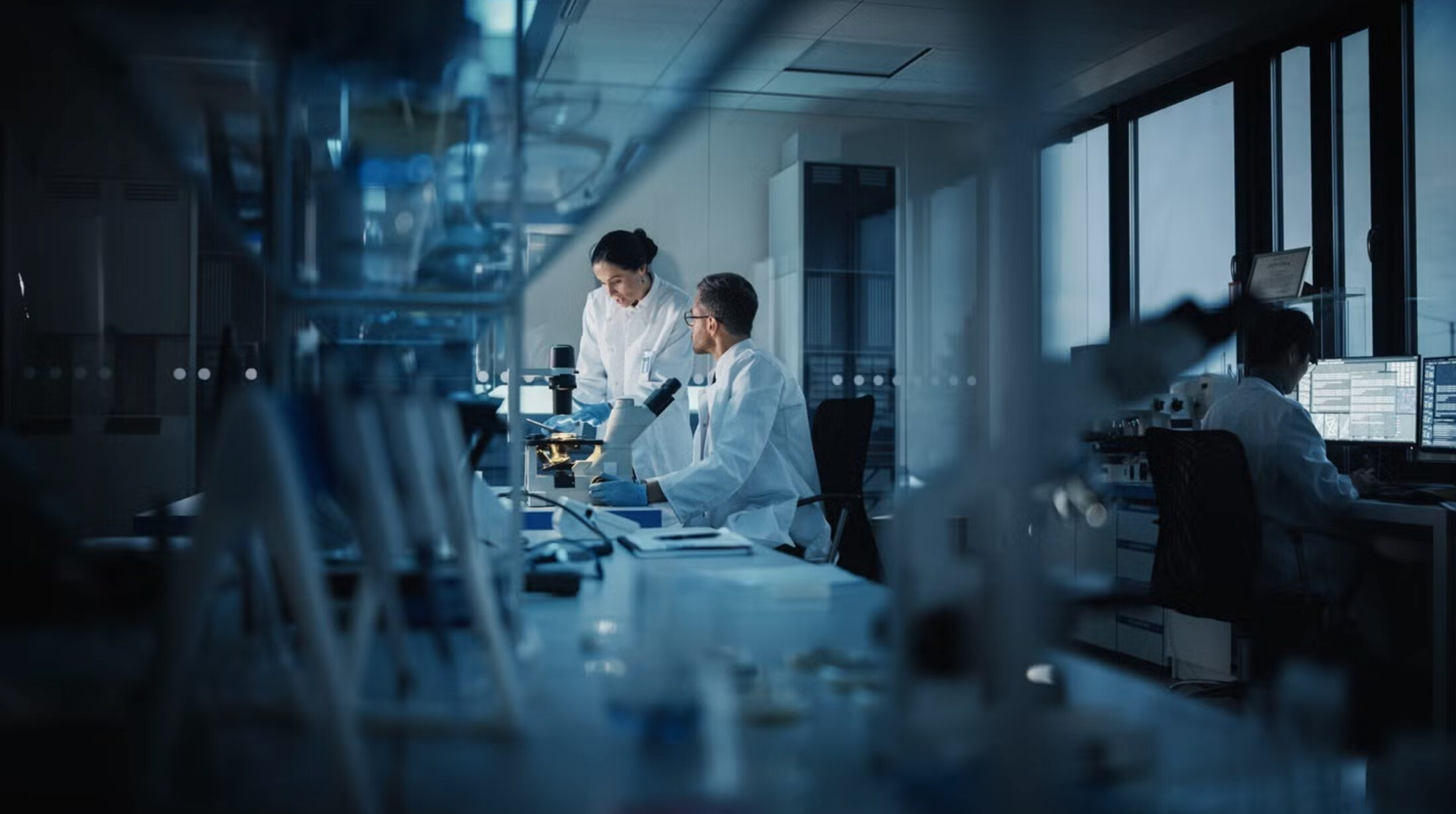 Scientists working at a microscope in a pharmaceutical research laboratory